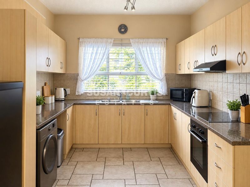 Functional U-shaped kitchen featuring light wood cabinetry, granite countertops, integrated oven, hob, and extractor fan with tiled flooring and backsplash.