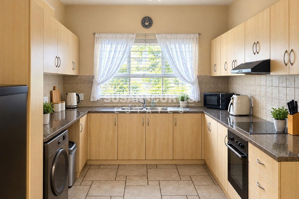 Functional U-shaped kitchen featuring light wood cabinetry, granite countertops, integrated oven, hob, and extractor fan with tiled flooring and backsplash.