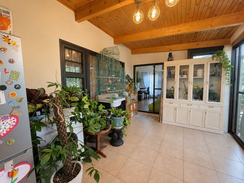 A sunroom or living area featuring a timber beam ceiling, tiled flooring, and built-in cabinetry with access to adjacent rooms via sliding glass doors.