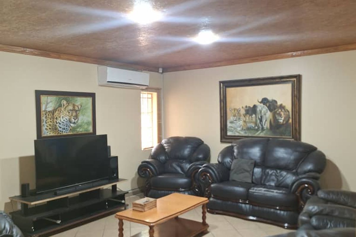 A living room featuring a textured ceiling, tiled flooring, and a wall-mounted air conditioning unit.