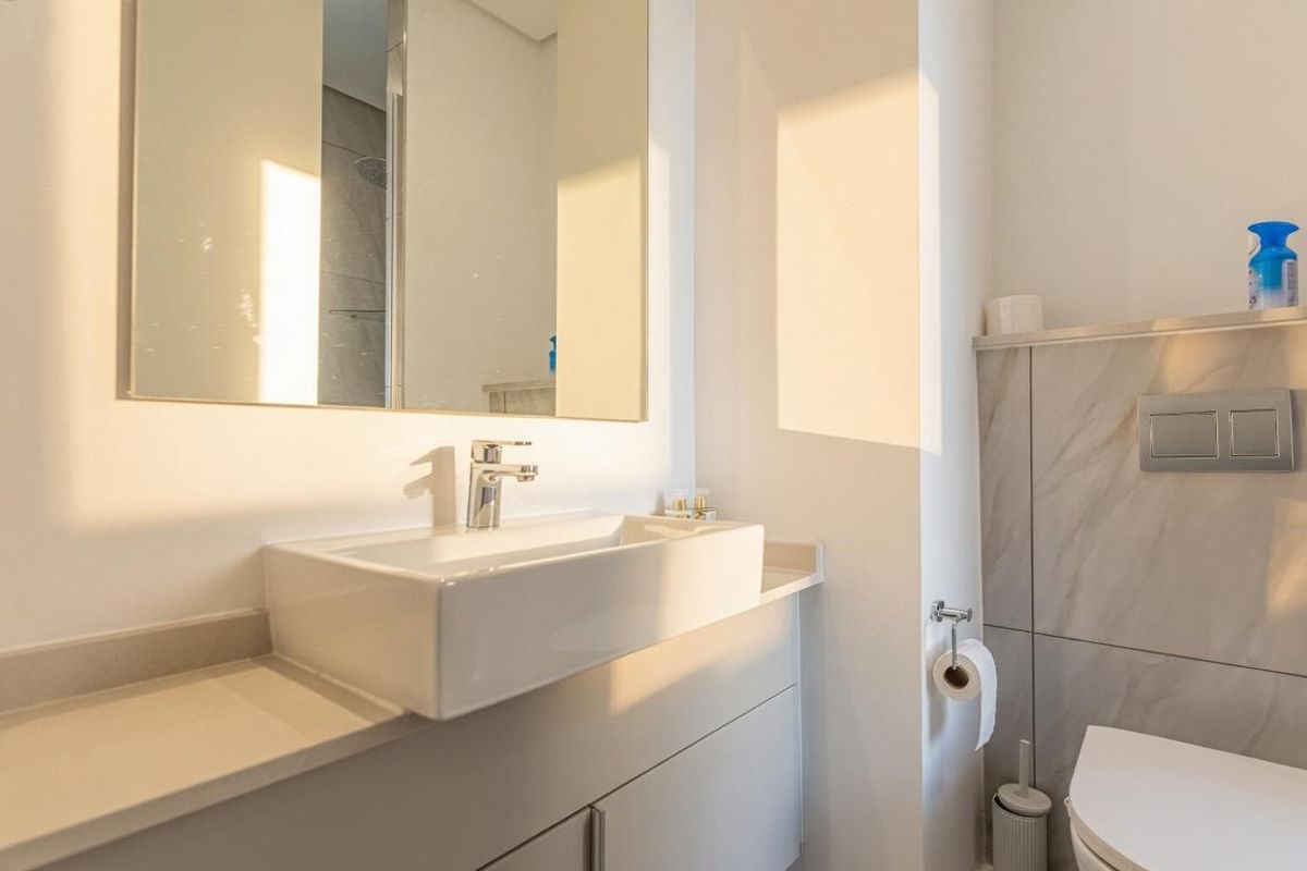 Modern bathroom featuring a wall-mounted vanity with a vessel sink, wall-hung toilet with concealed cistern, and elegant stone-look wall tiling.