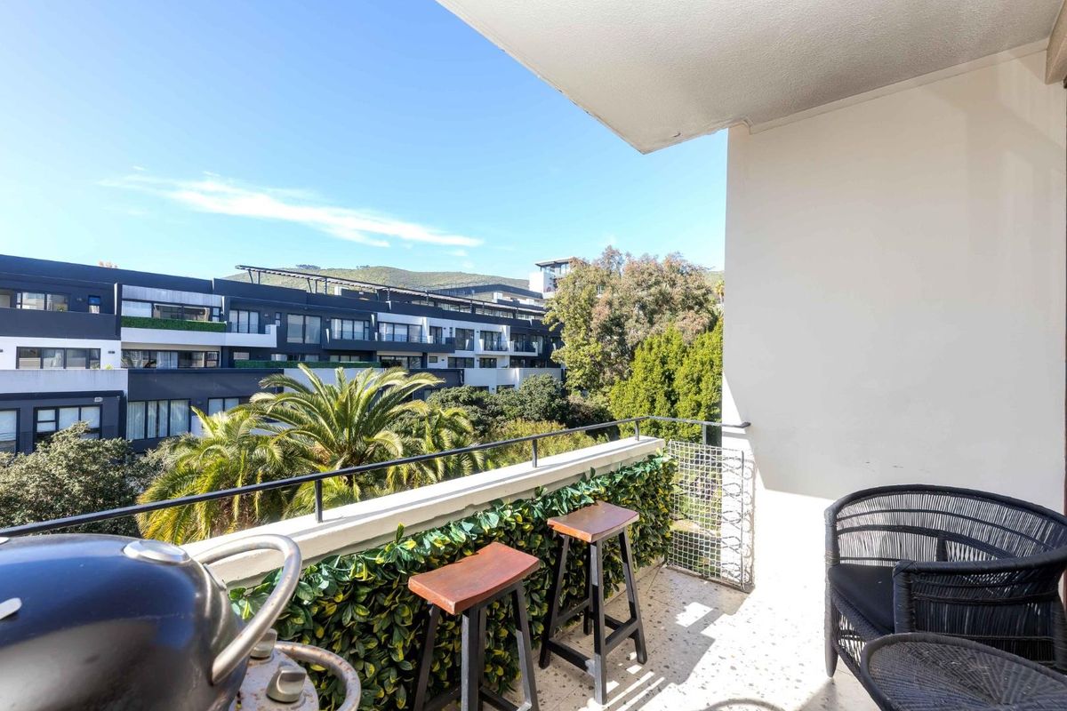 A well-maintained balcony featuring terrazzo flooring and a metal railing, offering pleasant views of the surrounding residential complex and greenery.