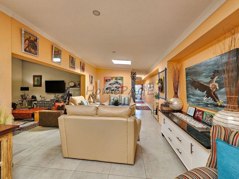 Spacious open-plan living area featuring tiled flooring, recessed lighting, and a skylight, creating a bright and connected living space.