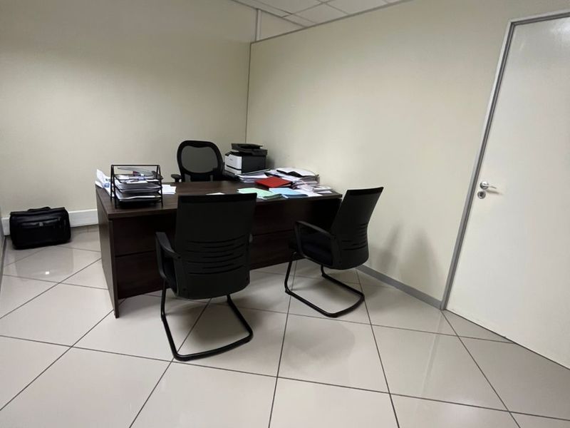 A functional office space featuring tiled flooring and a suspended ceiling, providing a clean and professional environment for work.
