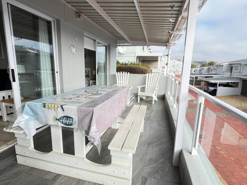 A covered balcony featuring tiled flooring, a glass balustrade, and sliding door access to the interior living space.