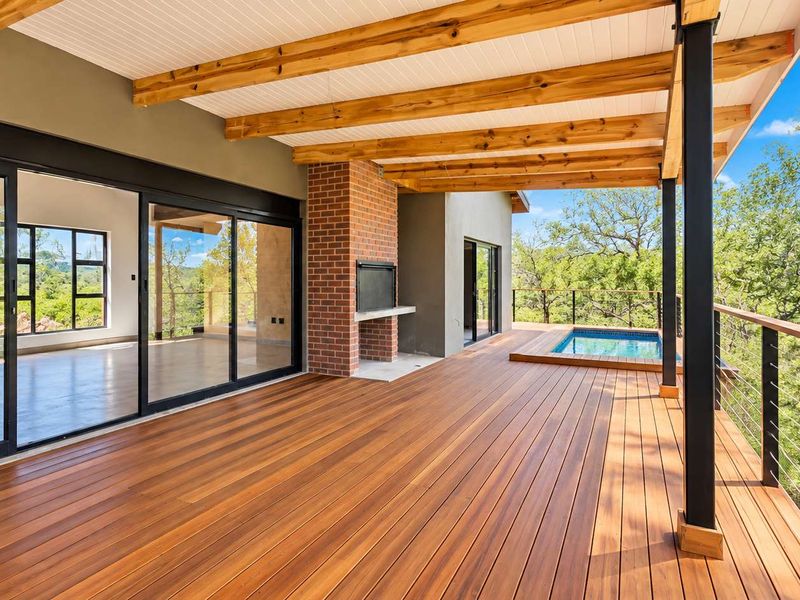 Spacious covered timber deck featuring a built-in brick fireplace, plunge pool, and expansive views, seamlessly connected to the interior via large sliding glass doors.