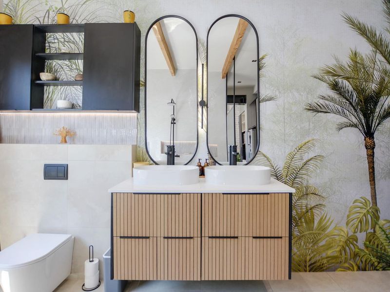 Modern bathroom featuring a double vanity with vessel sinks, black tapware, wall-mounted toilet, and decorative wall finishes with integrated lighting.