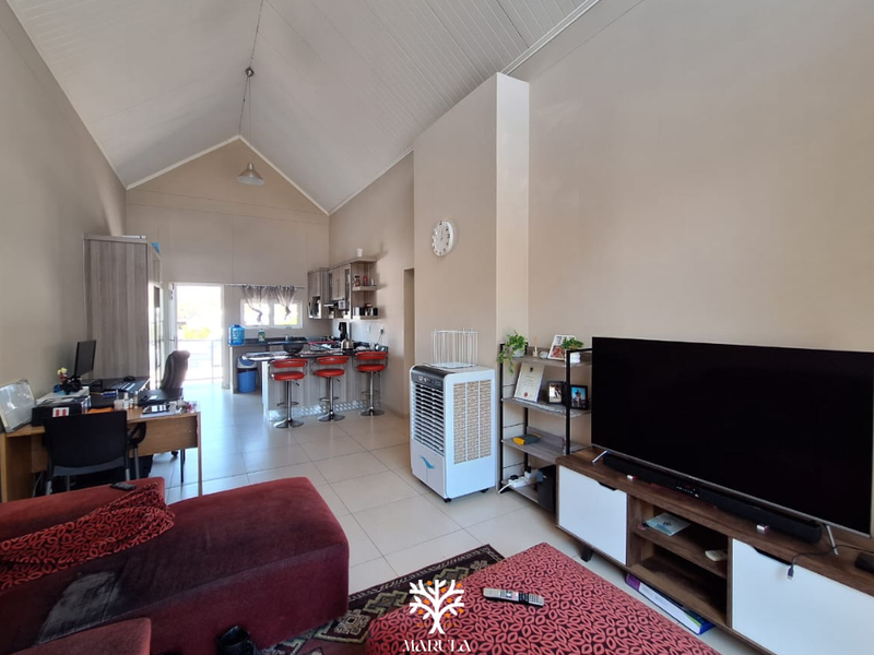 Open-plan living area featuring a vaulted ceiling, tiled flooring, and an integrated kitchen with a breakfast bar island.