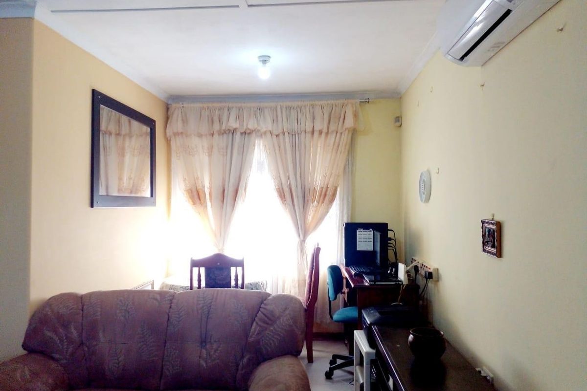 A living room featuring a split-system air conditioner, coving, and natural light through window curtains.