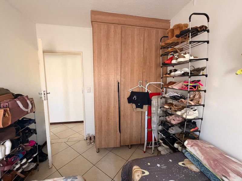 A bedroom featuring tiled flooring and a built-in wooden wardrobe, providing functional storage space within the room.