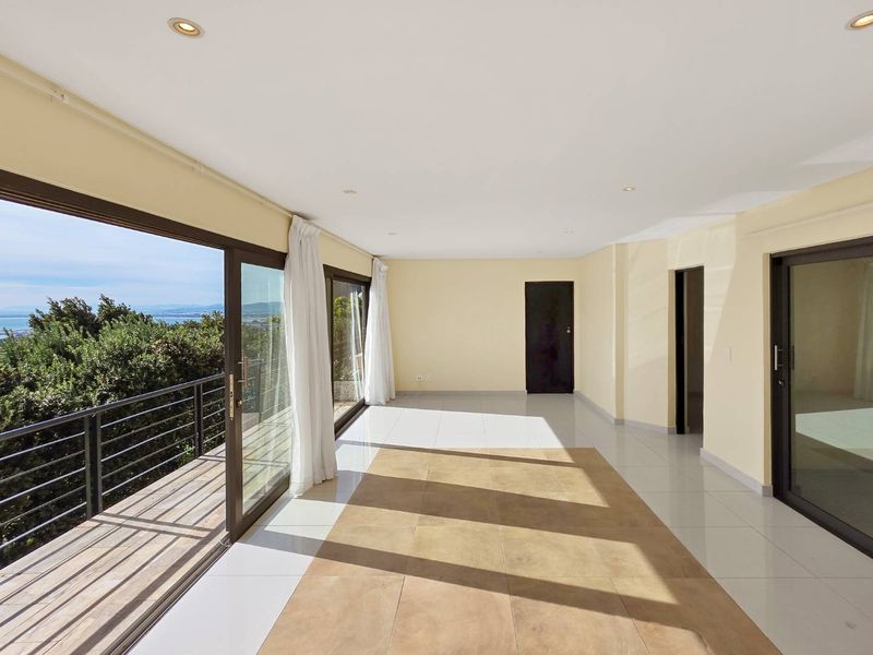 Spacious, light-filled living area featuring large sliding glass doors that open onto a balcony with scenic views and modern tiled flooring.