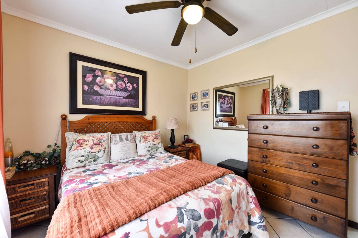 A cozy bedroom featuring tiled flooring, a central ceiling fan, and neutral wall finishes, providing a comfortable and functional sleeping space.