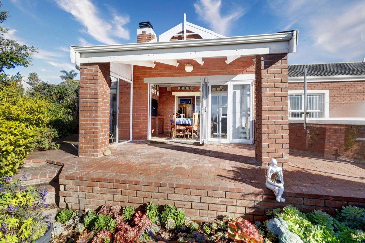 A well-maintained rear exterior featuring a covered brick patio with bi-fold doors leading into the main living area.