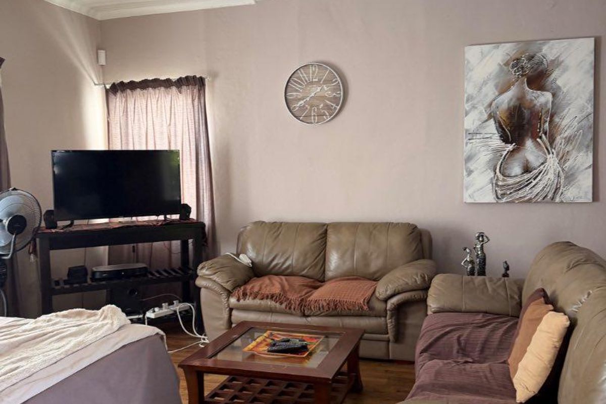 A living room featuring laminate flooring and recessed downlights, showing visible signs of ceiling water damage and plaster cracking.