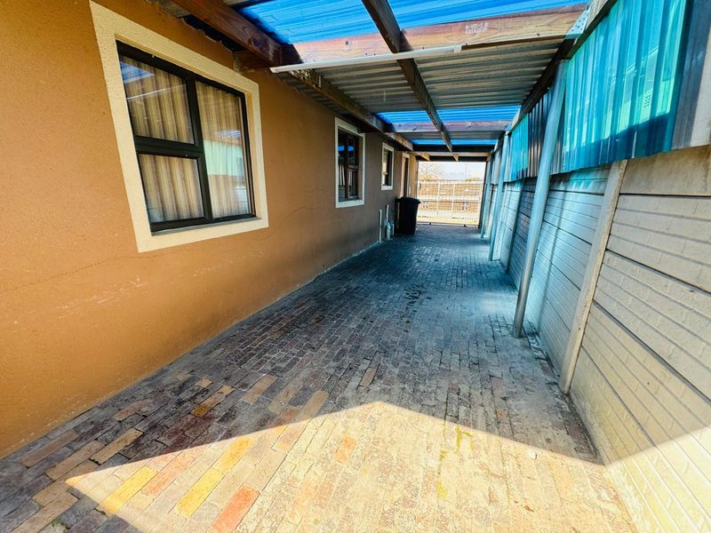 A covered outdoor walkway featuring brick paving and a timber pergola structure, providing a functional side access area for the townhouse.