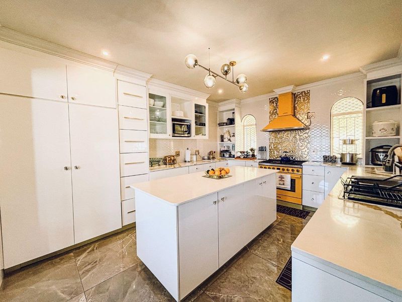 Modern kitchen featuring a central island, white cabinetry, quartz countertops, a vibrant yellow range with matching extractor, and elegant tiled flooring.