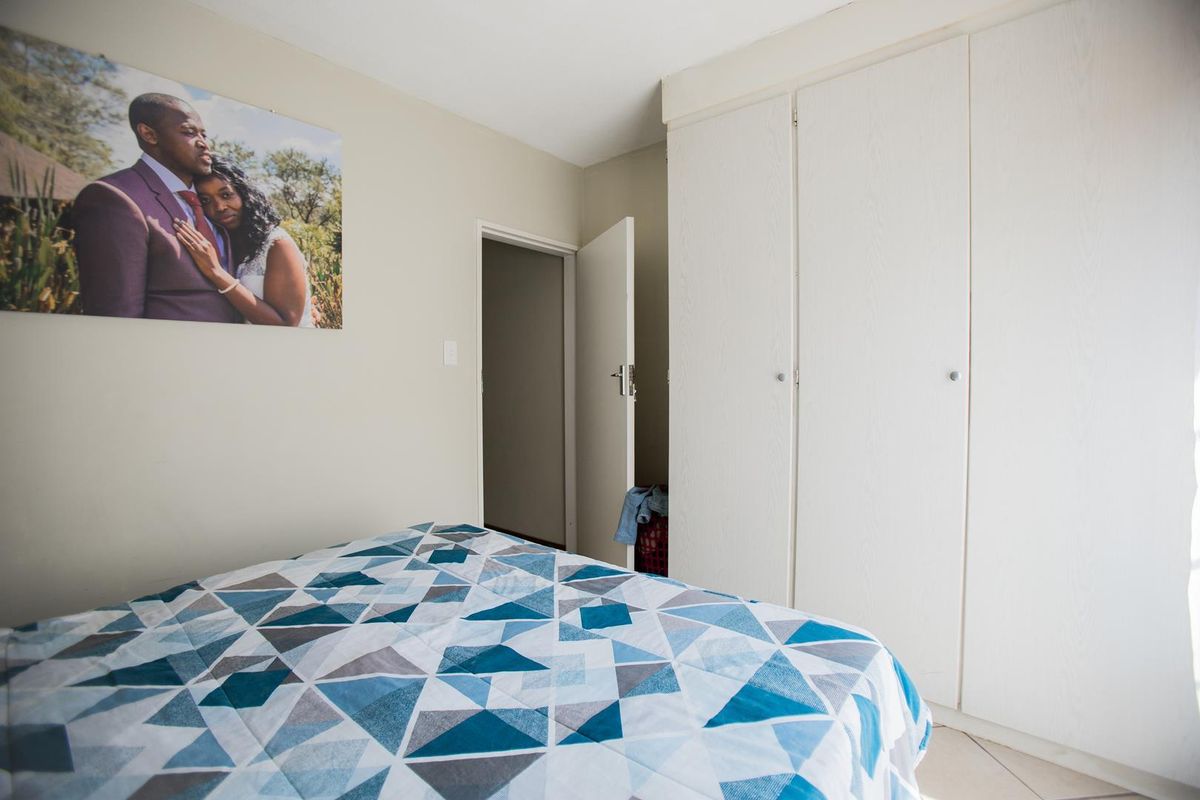 A bedroom featuring built-in wardrobes with white cabinetry and tiled flooring, providing functional storage space.