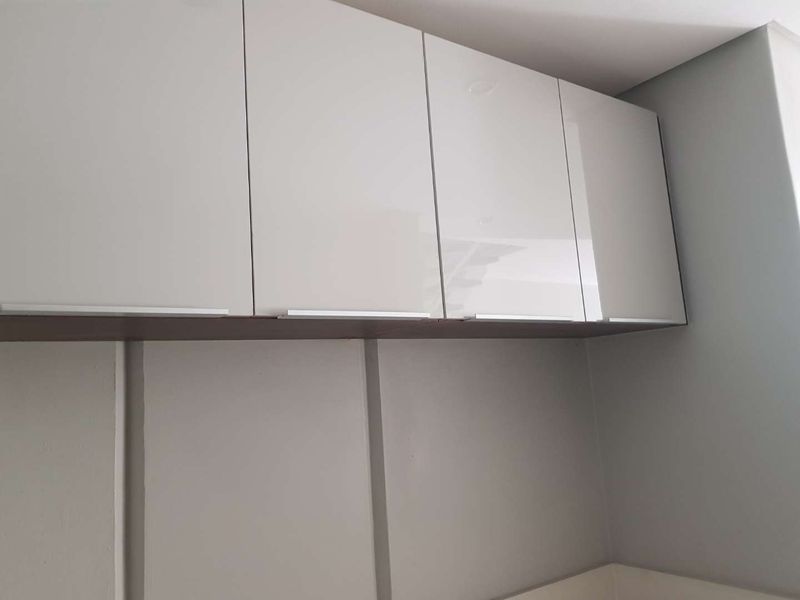 A close-up view of modern, high-gloss white wall-mounted kitchen cabinetry with integrated handles.