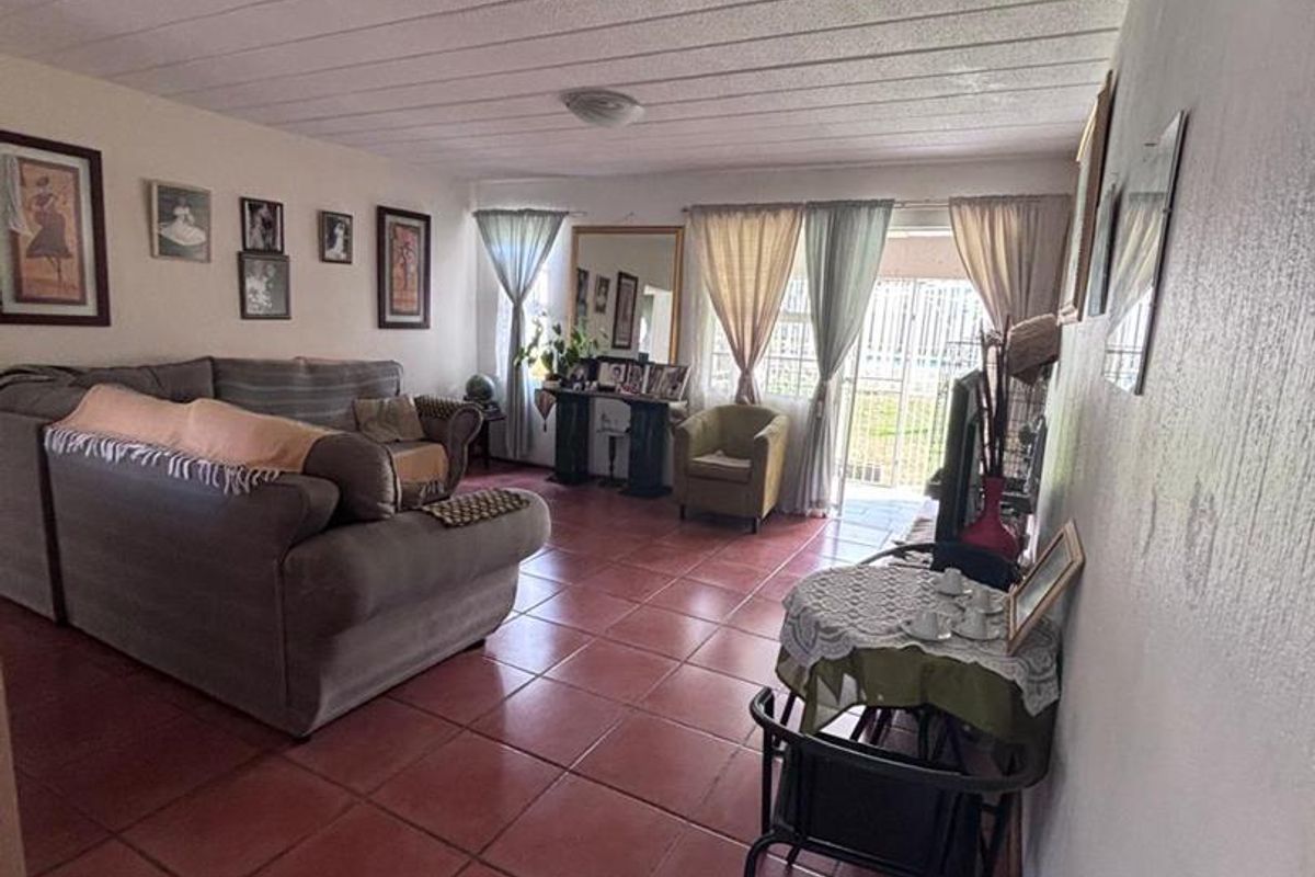 A spacious living area featuring terracotta floor tiles and a textured ceiling, with direct access to an outdoor patio area.