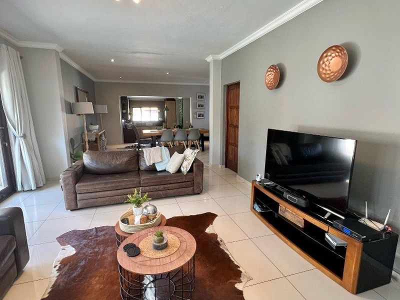 Spacious open-plan living area featuring neutral tiled flooring, modern recessed lighting, and seamless flow into the adjacent dining and kitchen space.