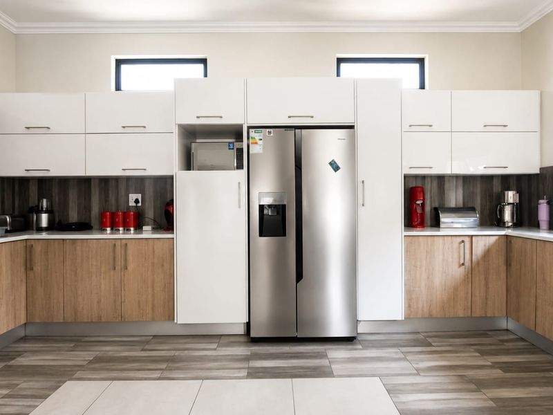 Modern kitchen featuring two-tone cabinetry, wood-look flooring, integrated microwave, and a large double-door refrigerator with ample counter space.
