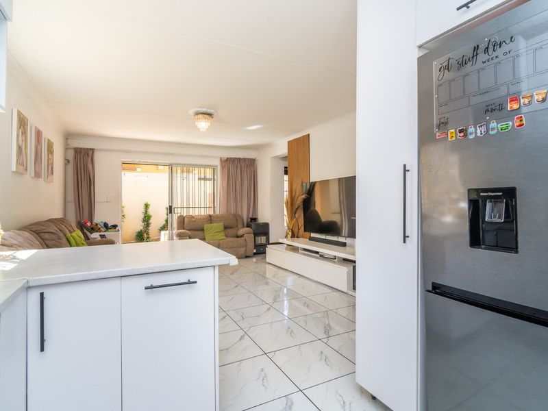 Open-plan living area featuring modern marble-look floor tiles, neutral cabinetry, and direct access to a private patio through sliding glass doors.