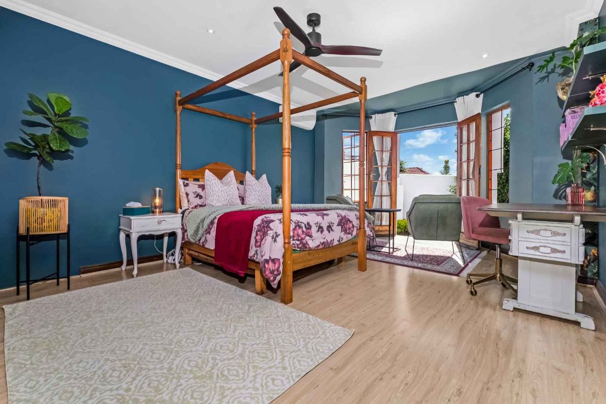 Spacious bedroom featuring light wood-look flooring, a ceiling fan, and double doors opening to an outdoor area.