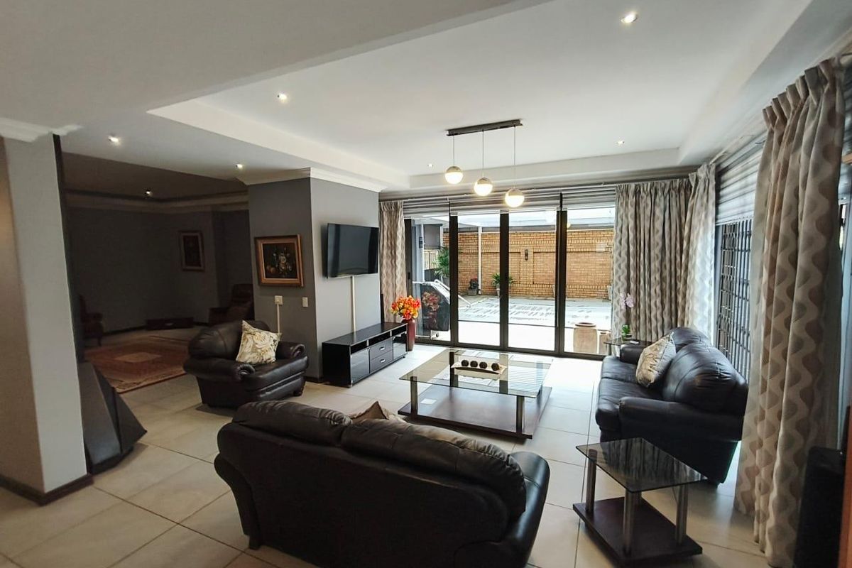 Spacious living room featuring large sliding glass doors that open to an outdoor area, complemented by recessed ceiling lighting and neutral tiled flooring.