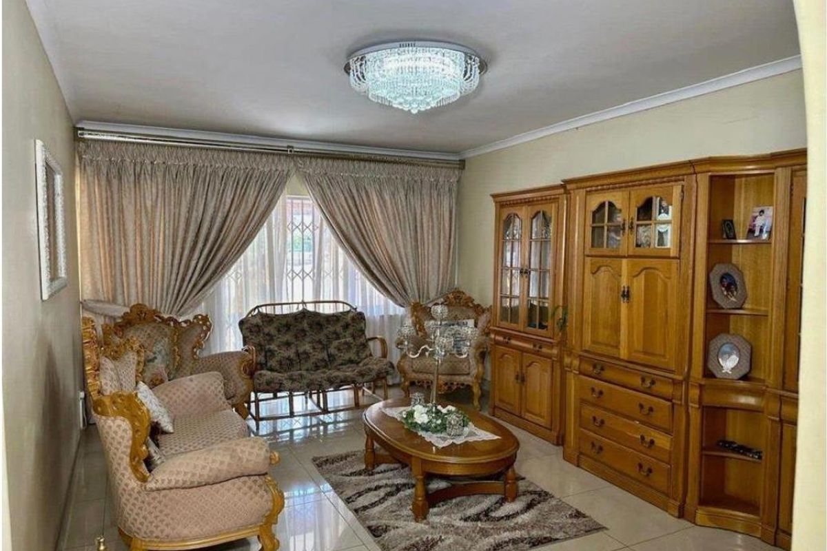 A formal living room featuring tiled flooring, a decorative crystal chandelier, and built-in wooden cabinetry.