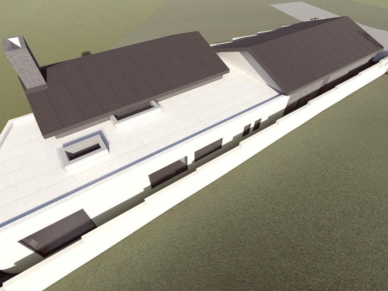 An aerial perspective of the property showing the roof structure, chimney, skylights, and surrounding boundary wall.