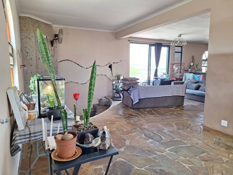 Spacious open-plan living area featuring natural flagstone flooring, coved ceilings, and large sliding glass doors that provide ample natural light and outdoor access.