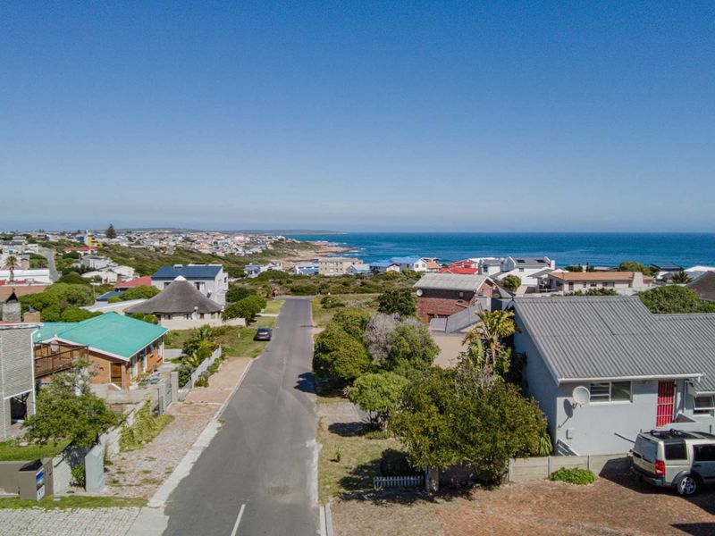 An aerial view of a coastal residential neighborhood, showcasing the surrounding street layout and proximity to the ocean.