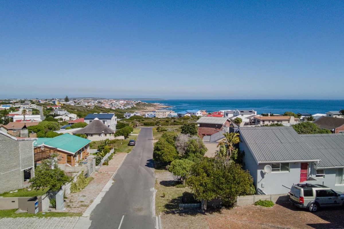 An aerial view of a coastal residential neighborhood, showcasing the surrounding street layout and proximity to the ocean.