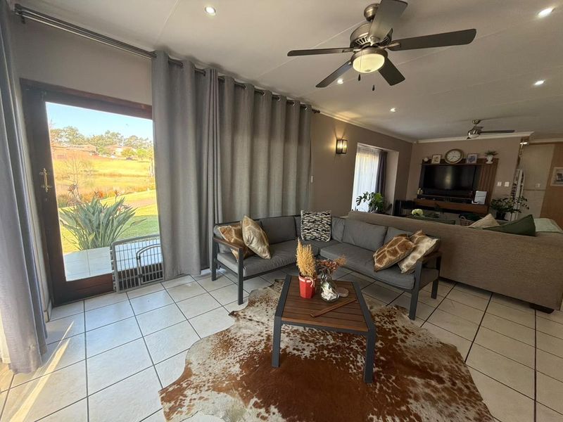 Spacious living room featuring tiled flooring, recessed lighting, ceiling fans, and a large sliding glass door providing natural light and garden access.
