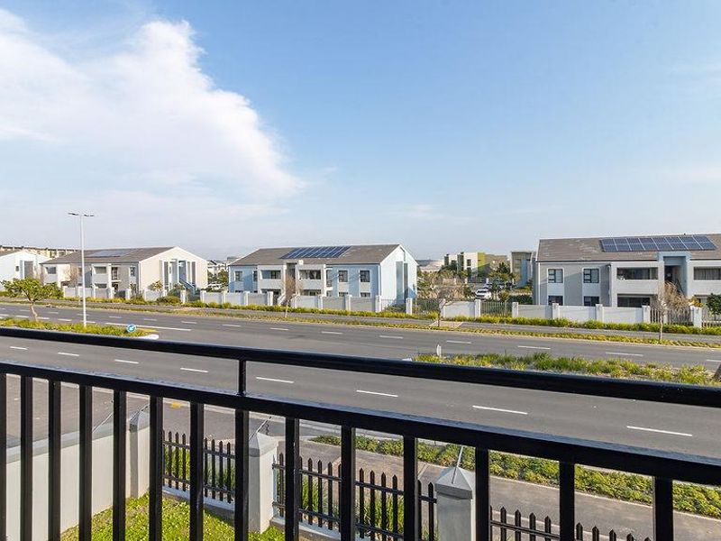 An elevated view overlooking a suburban street with residential apartment complexes featuring solar panels on the roofs.