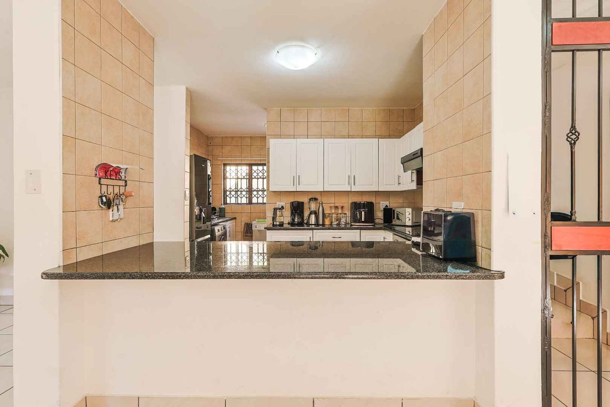 A functional kitchen featuring white cabinetry, a granite breakfast bar, and tiled backsplash, providing a practical layout for cooking and casual dining.