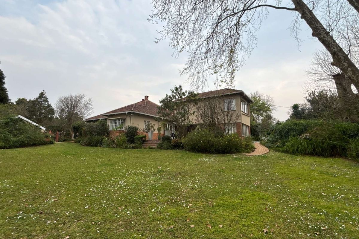 A view of the rear elevation of the house, featuring a large established garden, paved pathways, and traditional brick and tile construction.