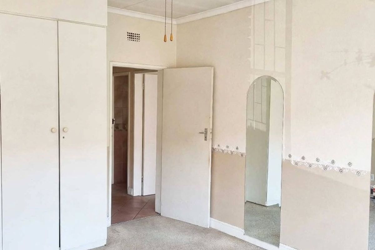 An empty bedroom featuring built-in cupboards, a ceiling fan, and carpet flooring, offering a blank canvas for renovation and modernization.