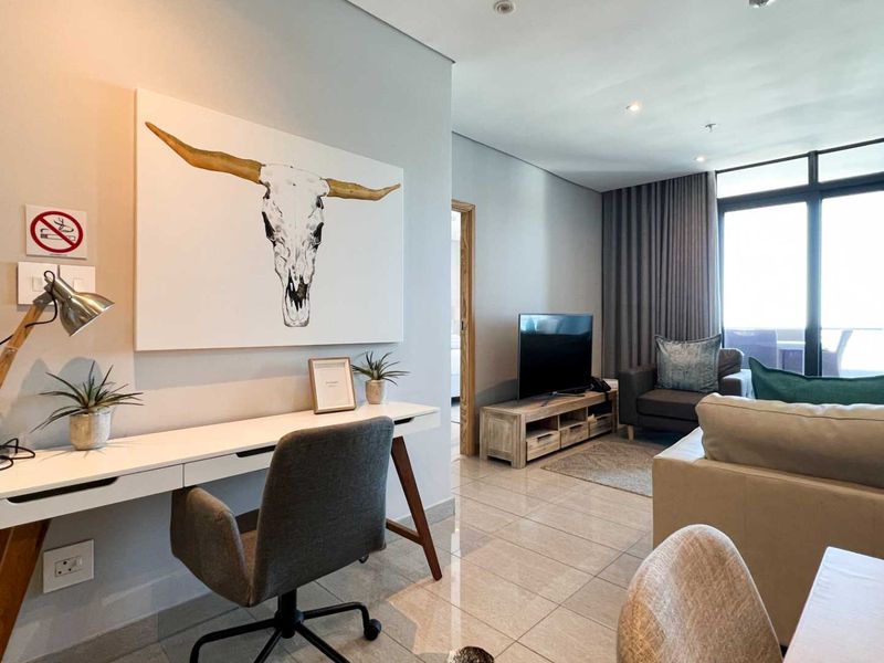 An open-plan living area featuring tiled flooring, recessed lighting, and large sliding glass doors leading to a balcony.