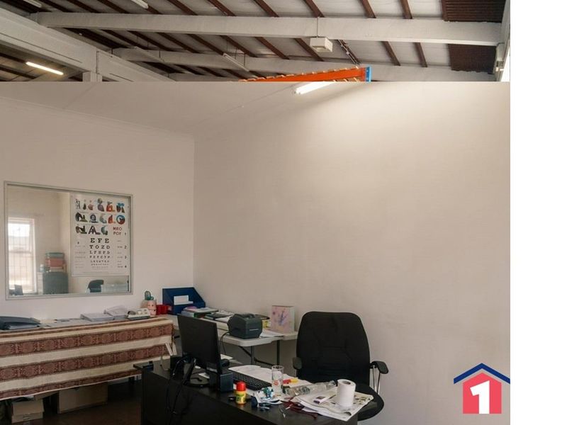 A functional office space featuring exposed ceiling beams and standard fluorescent lighting, suitable for administrative or industrial management use.