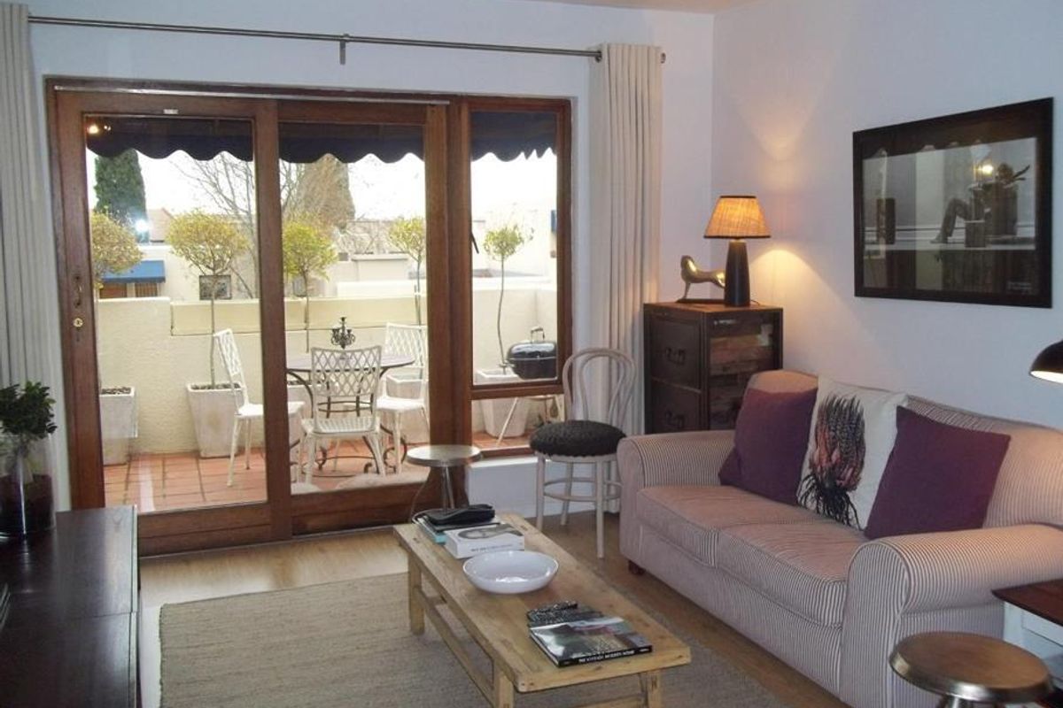 A cozy living room featuring laminate flooring and a large sliding glass door that provides direct access to an outdoor patio area.