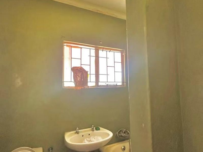 A basic bathroom featuring a pedestal basin, toilet, and bathtub, requiring cosmetic updates and finishing to improve its overall condition and appeal.