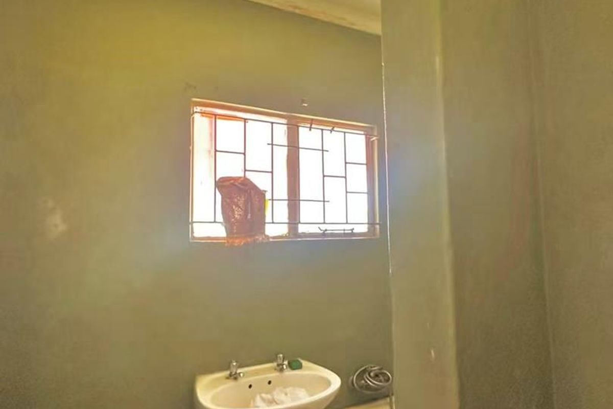 A basic bathroom featuring a pedestal basin, toilet, and bathtub, requiring cosmetic updates and finishing to improve its overall condition and appeal.