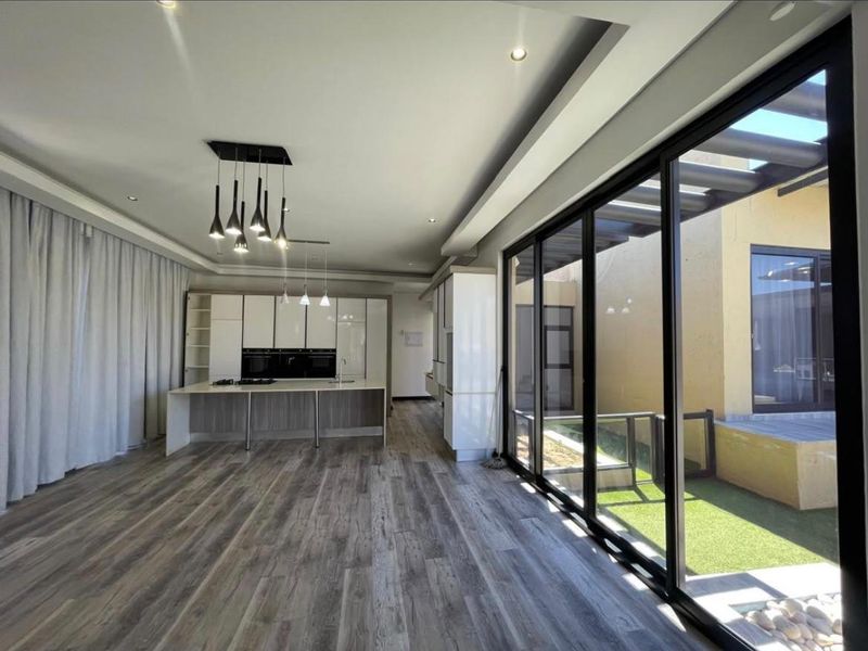 Spacious open-plan living and kitchen area featuring modern cabinetry, integrated appliances, and large sliding glass doors opening to an outdoor patio space.