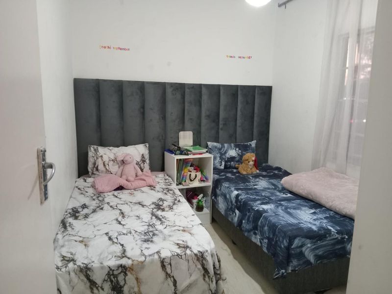 A compact bedroom featuring a shared upholstered headboard design, suitable for a twin or guest room setup.