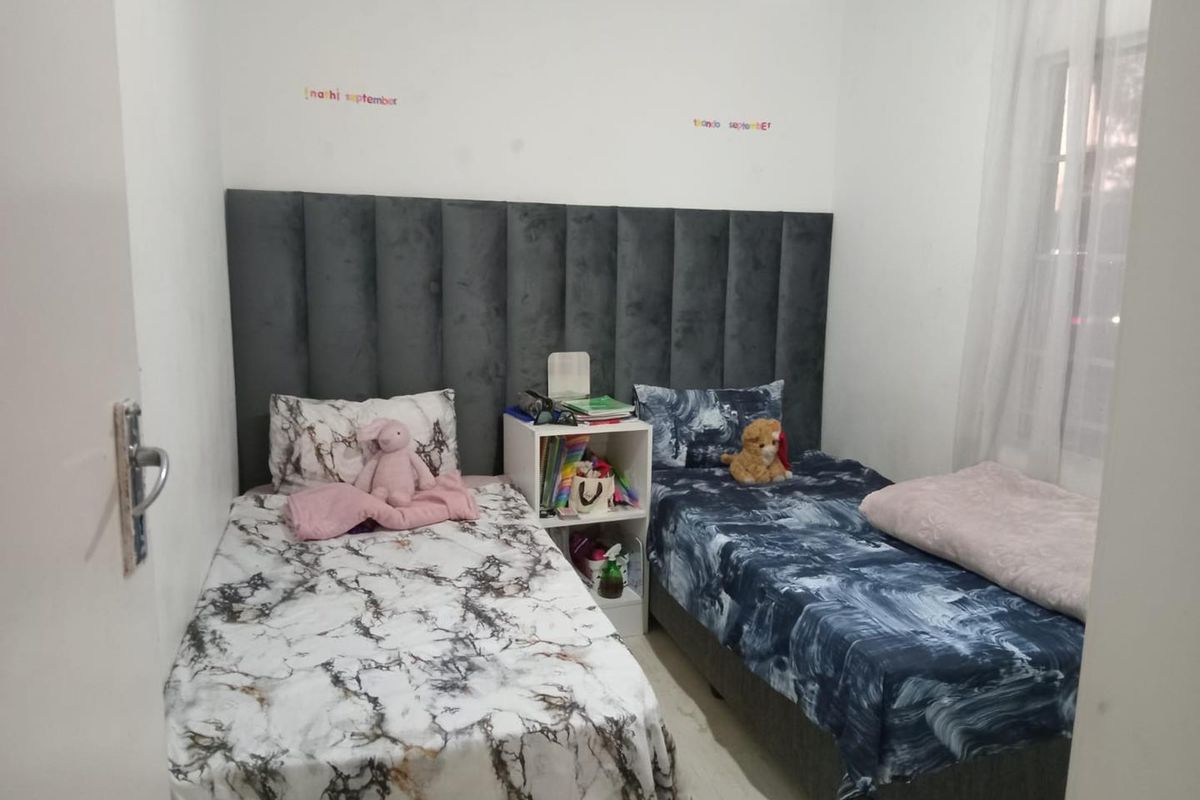 A compact bedroom featuring a shared upholstered headboard design, suitable for a twin or guest room setup.
