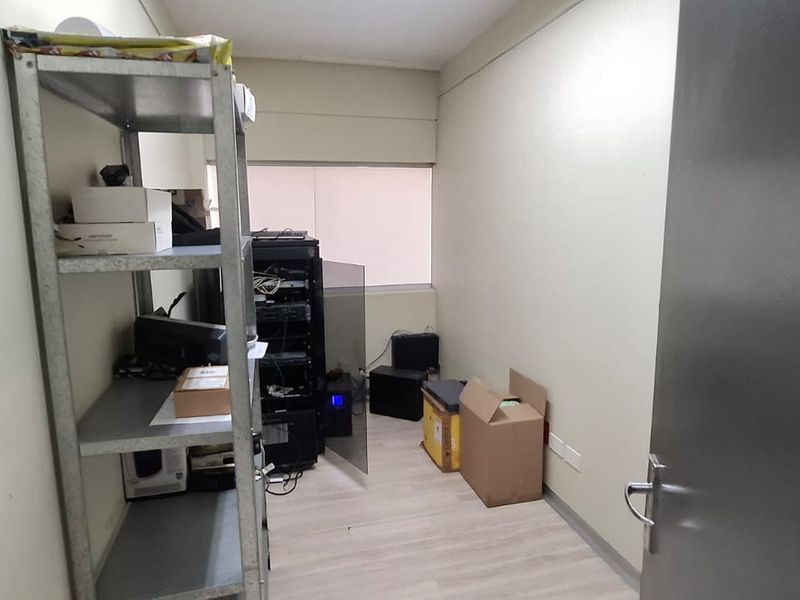 A functional utility or server room featuring laminate flooring and dedicated space for technical infrastructure and equipment storage.