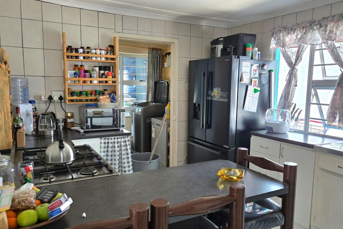 A functional kitchen featuring built-in cabinetry, a gas hob, and an adjacent scullery area with tiled walls and natural light.