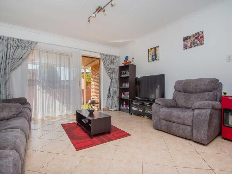 A living room featuring tiled flooring and a sliding glass door providing access to the outdoor area.