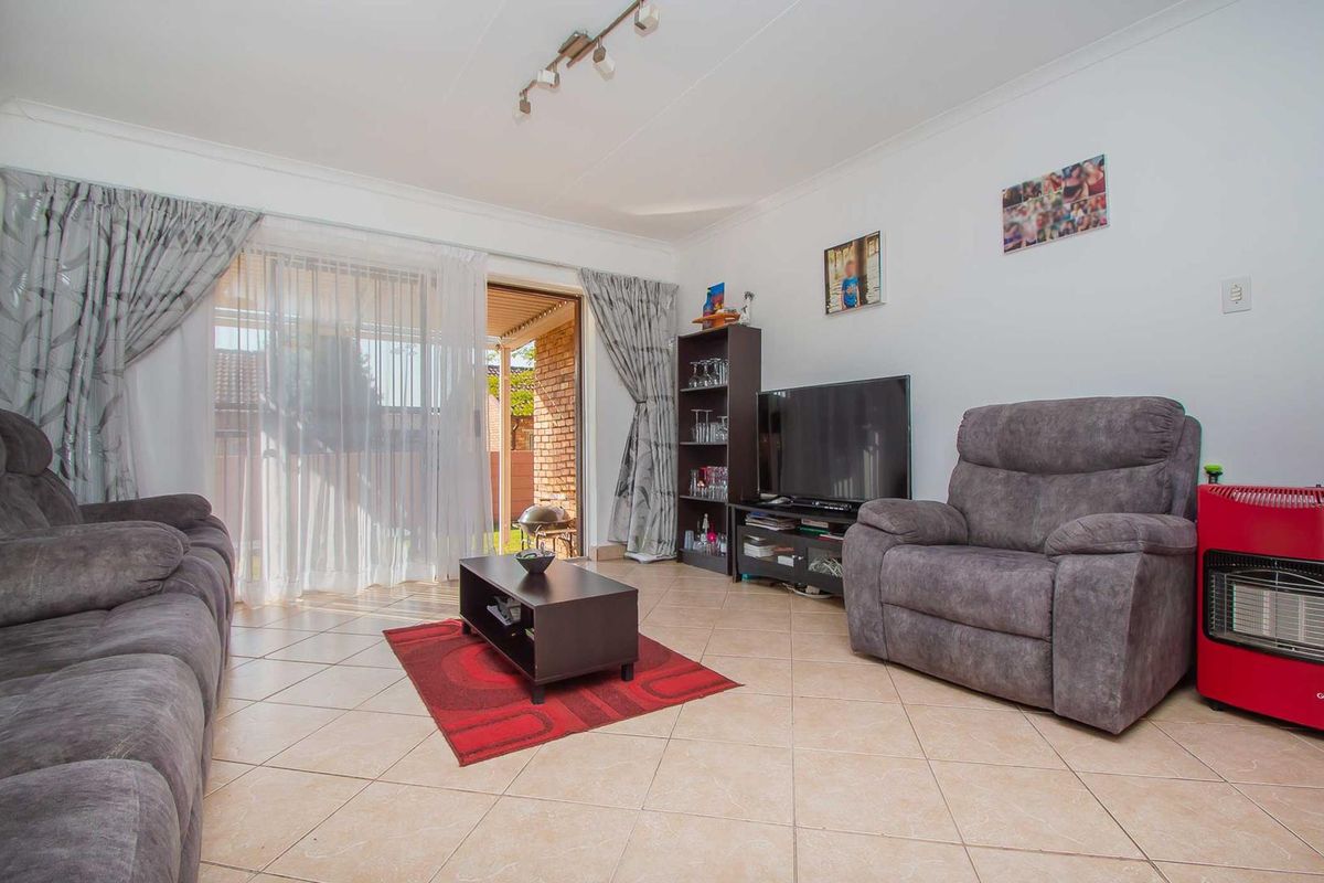 A living room featuring tiled flooring and a sliding glass door providing access to the outdoor area.